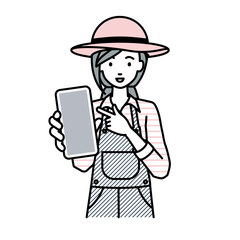 立ってスマートフォンを指差してこちらに向けて見せている農家の女性