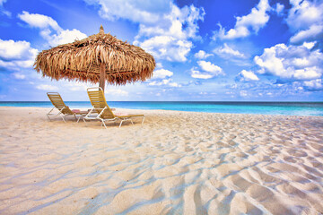 Thatch umbrella and deckchairs on an ideally sandy coast