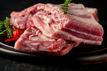 Raw pork ribs with spices and thyme on a dark wooden background