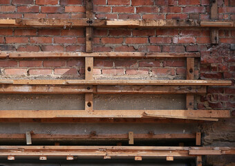 Old rough decaying brick wall with old wooden battens attached