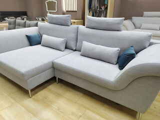 Beautiful stylish gray sofa with gray and dark blue pillows. Sofas in the furniture showroom. Sale of sofas