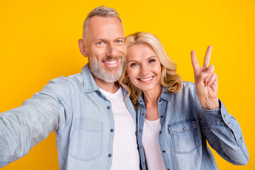 Photo of pensioner couple wife husband make selfie show v-sign smile enjoy isolated on yellow color...