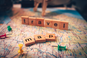 Wood square with word "map" and "travel" on the map. pushpin showing the location of a destination point on a map. Travel plan concept.