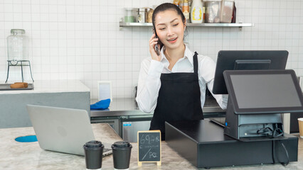 The owner of the shop receives a phone call to take coffee orders and has a barista making coffee in the coffee shop. 