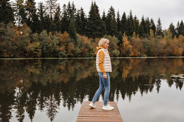 Fototapeta na wymiar The woman is in the autumn park. Autumn atmosphere, scenic view of the river