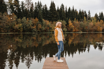 The woman is in the autumn park. Autumn atmosphere, scenic view of the river