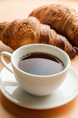 Selective focus composition with a cup of tea and croissants close-up.
