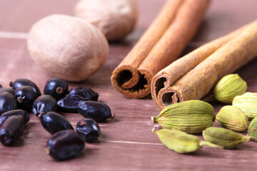 Cardamom, nutmeg, cinnamon and other aromatic spices lie on a wooden table