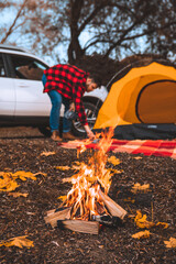 bonfire in front of camping site tent with car and person on background