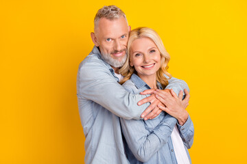 Photo of cheerful joyful happy old couple hug embrace care enjoy harmony hands isolated on yellow color background