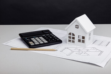 White house and calculator on drawing. House building costs concept