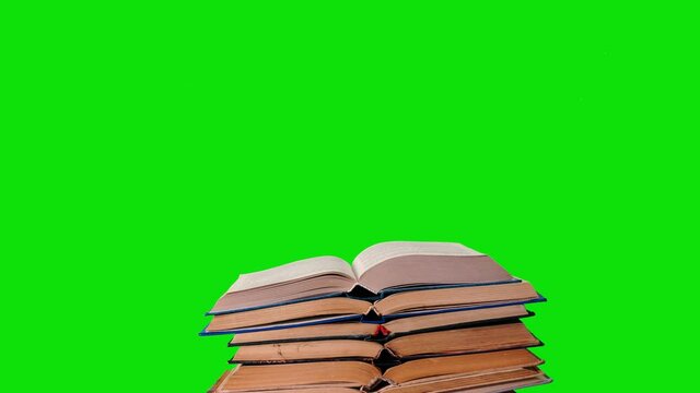 Lots of pile of books growing on green chroma key background. Teaching and learning science concept. A stack of books on a wooden table, stop motion, time laps.