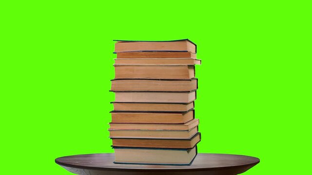 Lots of pile of books growing on green chroma key background. Teaching and learning science concept. A stack of books on a wooden table, stop motion, time laps.