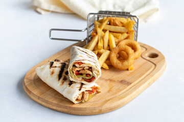 Chicken wrap on a white background. With french fries and onion rings