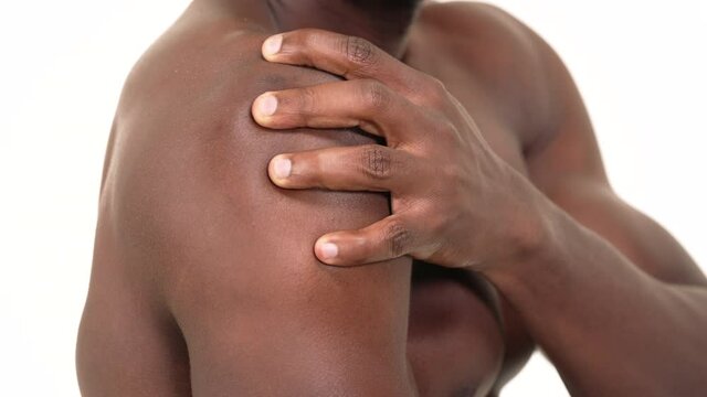 Close up of a black man massaging his shoulder. Isolated on a white background.
