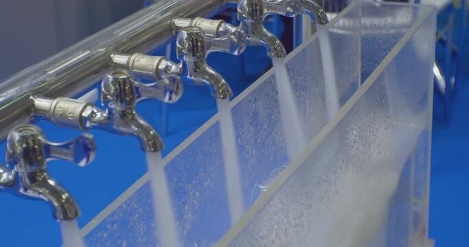 jets of clean water are poured from several metal mixer taps.Close-up.