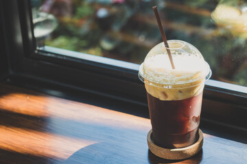 Side view of iced dark cold brew americano coffee on the plastic cup and brown plastic straw on the...