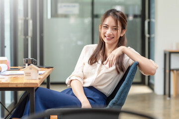 Beautiful young Asian businesswoman sitting in a chair looking at the camera at office.
