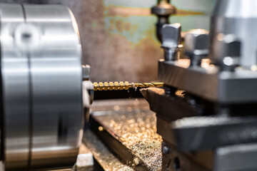 A turner drills a hole in a bronze hexagon on a lathe.