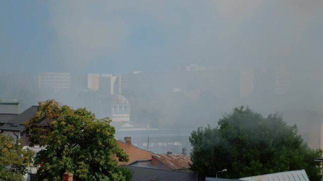 Urban landscape of city with smoke from burning house. View of city with smog and fumes from building on fire. Air with steam and flames from accident with dangerous fire in town.