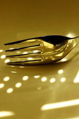 close-up metal fork with shadows on yellow background 