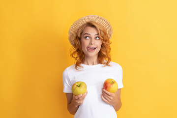 cheerful redhead woman in straw hat hold apple licking lips, dietary