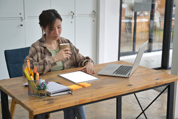 Photo of the university students is tutoring while sitting at the wooden working desk surrounded by a computer laptop and stationery.