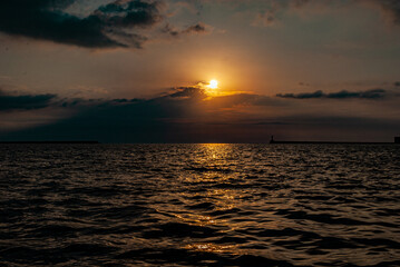 a soft calm sunset over a calm sea, when the setting sun is reflected in the water, and the sun sinks into dark clouds