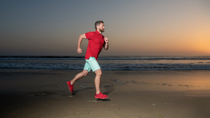 athletic man runner running on sunset summer beach, stamina