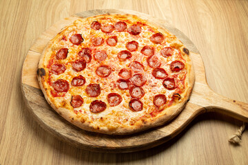 Traditional pizza with spicy sausage on a rustic wood background.
