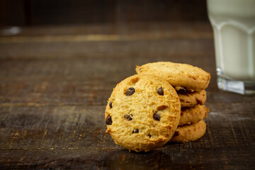 Pile of Chocolate chip cookie and glass of milk on rustic wooden background.