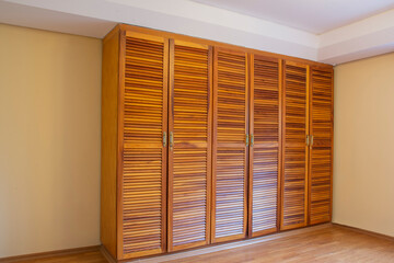solid wood wardrobe with six doors in empty parquet floored room