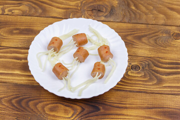 Spaghetti with sausages in the shape of spiders for Halloween party on wooden table