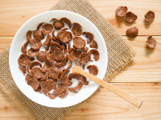 Chocolate breakfast cereal in a white bowl on wooden table