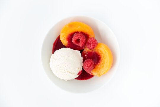 Scoop of Vanilla Ice Cream with Peach Halves, Raspberries and Raspberry Sauce