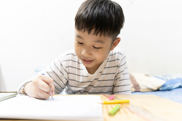 Home school and new normal lifestyle concepts.Asian boy studying through online media and do homework at home due to social distance policy to prevent the spread of the coronavirus(Covid-19)