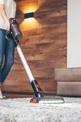 oman cleaning floor and carpet with cordless vacuum cleaner at home.