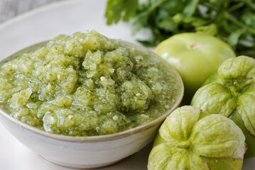 Close-up view of tomatillo green salsa (salsa verde cruda) in a bowl. Traditional Mexican cuisine.