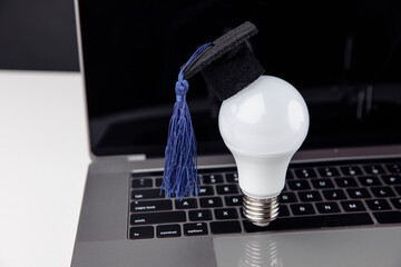 Graduation hat on light bulb on laptop. Online education concept