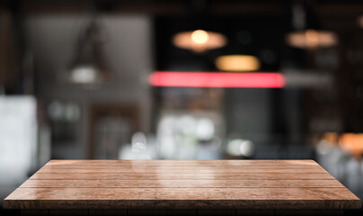 Empty wooden table top with lights bokeh on blur restaurant background.