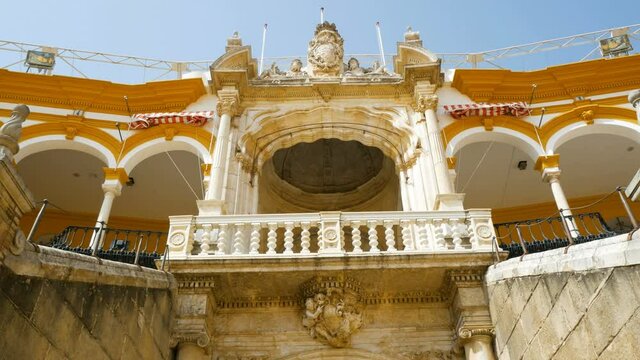 Entrance gate of the bulls arena in Seville, Spain, where the famous corridas take place. The construction is ancient and finely decorated. Blue sky on the background.