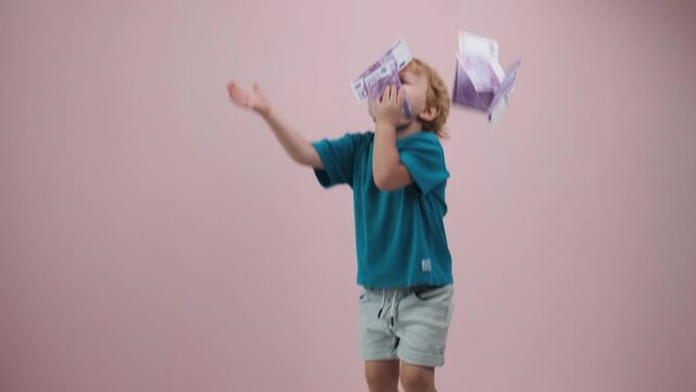 A little happy boy with money dancing on the floor. 4K