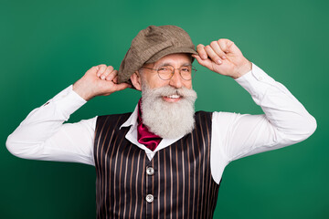 Photo of cheerful smart senior detective toothy white smile wear hat glasses striped suit scarf on green color background