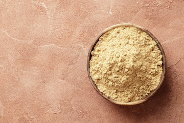 Wooden bowl full of dry ginger on textured background
