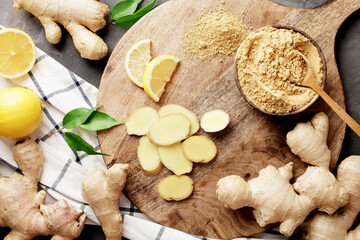 a lot of different ginger on a wooden kitchen board with lemons. Ginger dry and fresh, slides of...