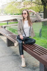 Beautiful young fashion stylish woman with eyeglasses sitting on the bench