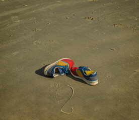 Colourful trainers left lying on a sandy beach 