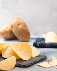 A classic flavour potato chips with potatoes at the background on a rustic blue background