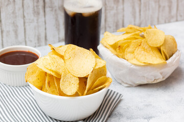 A bowl of seaweed flavoured potato chips and a basket of sour cream flavour chips, together with a glass of soft drink, a perfect snack!