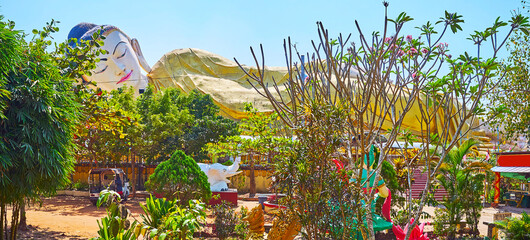 Reclining Buddha through the garden's greenery, Mya Tha Lyaung Buddha Temple, Bago, Myanmar